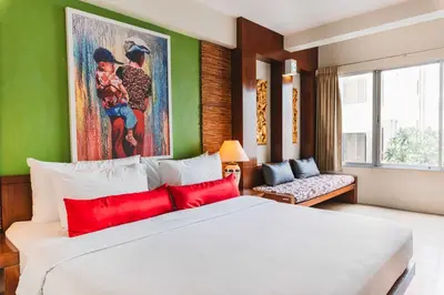 a bedroom with a large white bed with red pillows at Villa Cha-Cha Banglumphu in Bangkok