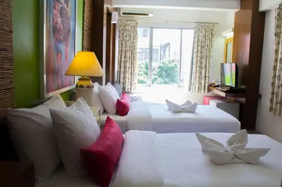 a hotel room with two beds and a window at Villa Cha-Cha Banglumphu in Bangkok