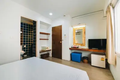 a bedroom with a white bed and a television at Villa Cha-Cha Banglumphu in Bangkok
