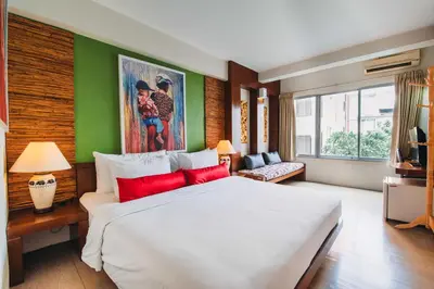 a bedroom with a large white bed with red pillows at Villa Cha-Cha Banglumphu in Bangkok