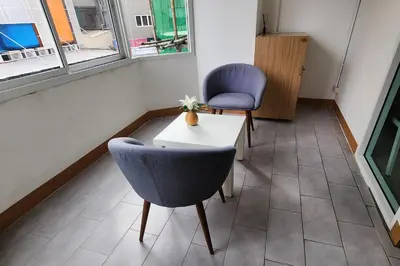 a room with two chairs and a table and two windows at Ease Hostel in Bangkok