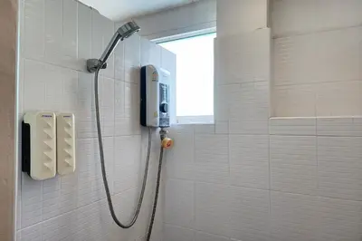 a shower in a bathroom with a phone on the wall at Ease Hostel in Bangkok