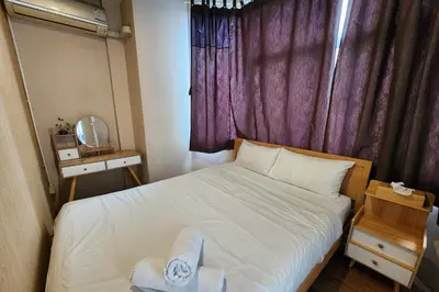 a small bedroom with a bed with a purple curtain at Ease Hostel in Bangkok