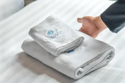 a person holding a pair of white socks on a bed at De Lavender Bangkok Hotel in Bangkok