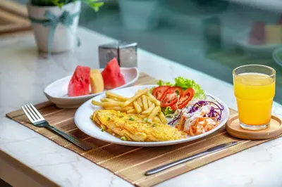 a breakfast plate of food and a glass of orange juice at De Lavender Bangkok Hotel in Bangkok