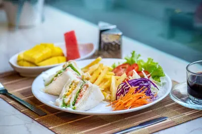 a plate of food with a sandwich and french fries at De Lavender Bangkok Hotel in Bangkok