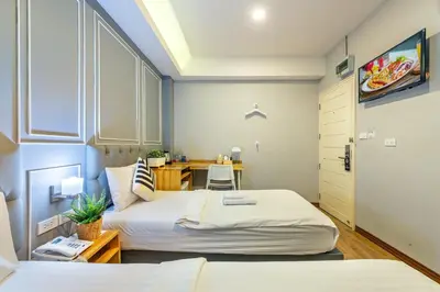 a small bedroom with two beds and a desk at De Lavender Bangkok Hotel in Bangkok