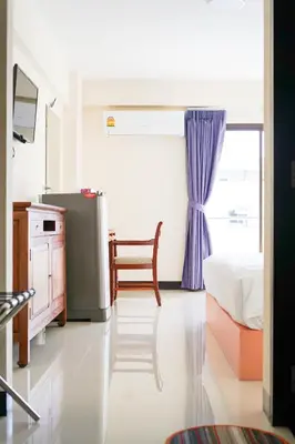 a bedroom with a bed and a chair and a window at White House Bizotel in Bangkok