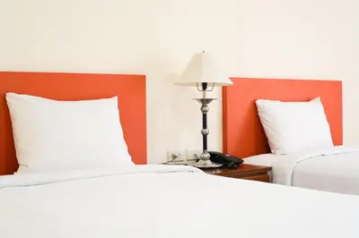 a hotel room with two beds and a lamp at White House Bizotel in Bangkok