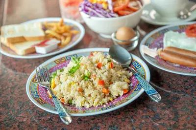 a plate of food with rice and vegetables on a table at Ama Hostel Bangkok in Bangkok