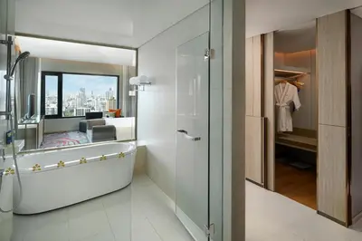 a bathroom with a shower and a bedroom with a view at Hotel Nikko Bangkok in Bangkok