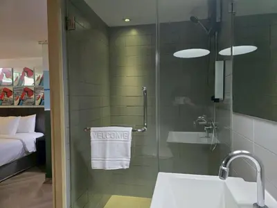 a bathroom with a shower with a sink and a towel at Somewhere to Escape - Hometel in Bangkok