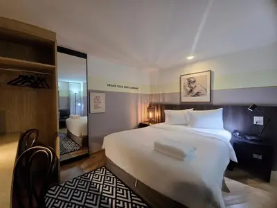 a hotel room with a large white bed and a mirror at Somewhere to Escape - Hometel in Bangkok