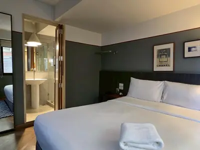 a bedroom with a large white bed and a bathroom at Somewhere to Escape - Hometel in Bangkok