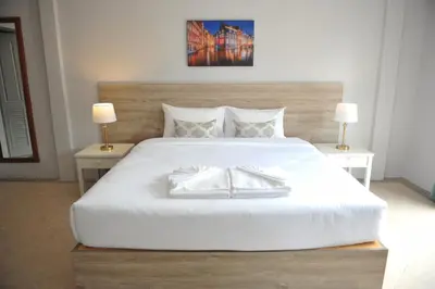 a bedroom with a large white bed with two lamps at Drop Inn Bangkok in Bangkok