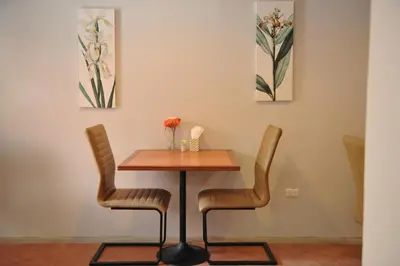 a table and chairs in a room with paintings at Drop Inn Bangkok in Bangkok