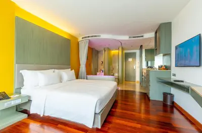 a bedroom with a large white bed and a bathroom at LiT BANGKOK Hotel in Bangkok