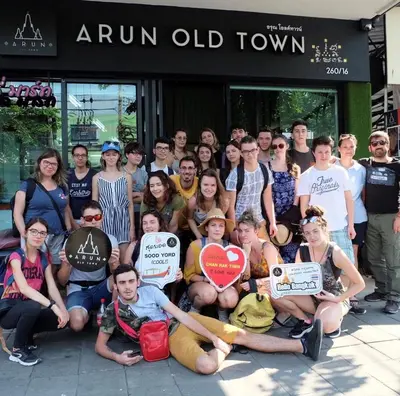 a group of people posing for a picture with signs at Arun Old Town in Bangkok