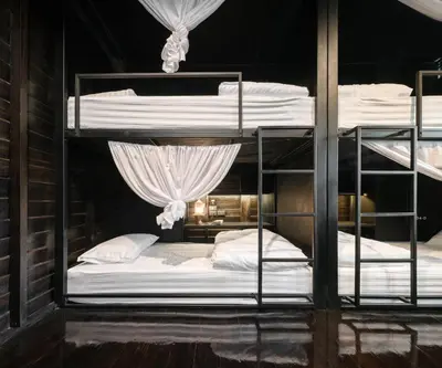 a room with three bunk beds with white sheets at Kloem Hostel in Bangkok