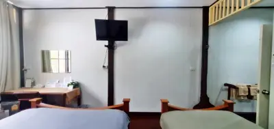 a room with two beds and a tv on the wall at OB ARUN House in Bangkok