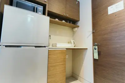 a kitchen with a white refrigerator and a wooden door at Thomson Residence Hotel in Bangkok