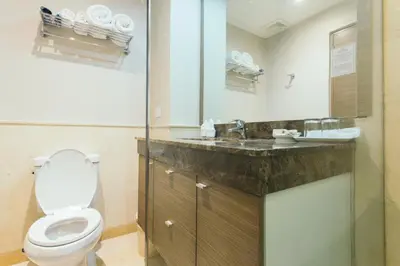 a bathroom with a toilet and a sink at Thomson Residence Hotel in Bangkok