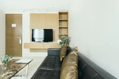 a living room with a brown couch and a tv at Thomson Residence Hotel in Bangkok