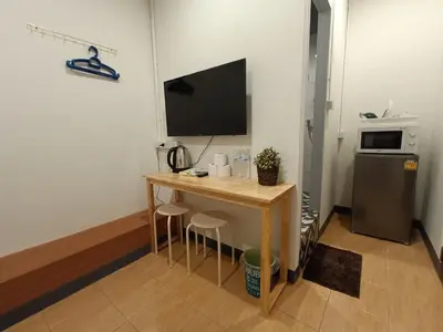a small room with a desk with a television and a refrigerator at My Home N1 - BTS Ratchathewi in Bangkok