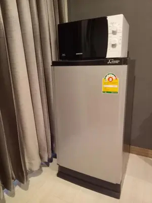 a microwave sitting on top of a refrigerator at My Home N1 - BTS Ratchathewi in Bangkok