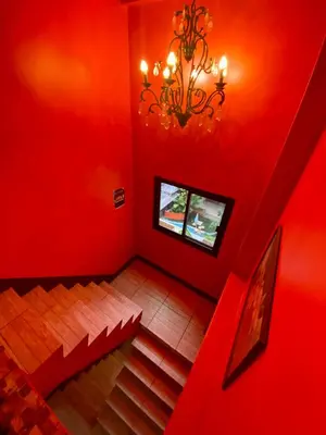 a red room with stairs and a chandelier at 4J Lodge in Bangkok