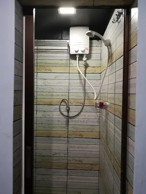 a shower in a bathroom with a wooden wall at 4J Lodge in Bangkok