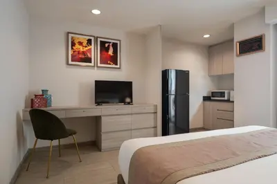 a bedroom with a bed and a desk and a refrigerator at Aspira Residence Ruamrudee in Bangkok