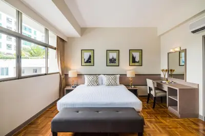 a bedroom with a bed and a desk and windows at Asoke Residence Sukhumvit by UHG in Bangkok