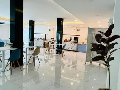 a lobby with tables and chairs and a kitchen at Bed by Tha-Pra SHA Plus in Bangkok