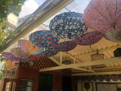 a group of colorful umbrellas hanging from a ceiling at Baan Tepa Boutique House in Bangkok