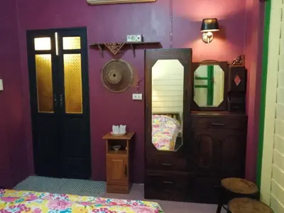 a bedroom with purple walls and a mirror and a bed at Baan Tepa Boutique House in Bangkok