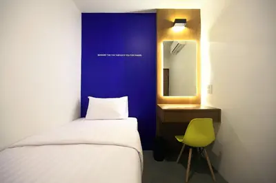 a bedroom with a bed and a mirror and a chair at Tuk Tuk Hostel in Bangkok