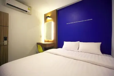 a bedroom with a white bed with a blue wall at Tuk Tuk Hostel in Bangkok