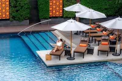 a woman sitting in a chair next to a swimming pool at The Westin Grande Sukhumvit, Bangkok in Bangkok