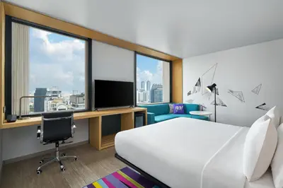 a hotel room with a bed and a desk and a tv at Aloft Bangkok - Sukhumvit 11 in Bangkok