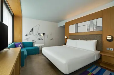 a bedroom with a large white bed and a blue couch at Aloft Bangkok - Sukhumvit 11 in Bangkok