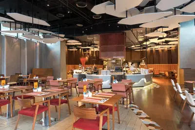 a restaurant with wooden tables and chairs and a kitchen at Aloft Bangkok - Sukhumvit 11 in Bangkok