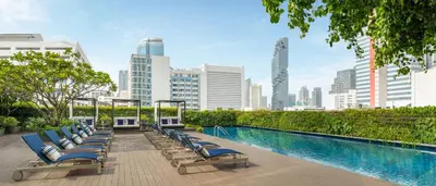 a row of chaise lounge chairs next to a swimming pool at Le Meridien Bangkok in Bangkok