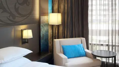 a room with a bed and a chair and a table at Paradox Bangkok Sukhumvit in Bangkok
