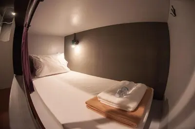 a small bed in a small room with a mirror at Tian Tian Hostel in Bangkok