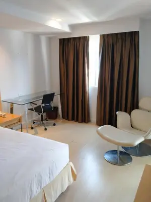 a hotel room with a bed and a desk and chairs at The Tivoli Hotel in Bangkok