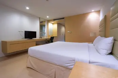 a hotel room with a white bed and a television at The Tivoli Hotel in Bangkok