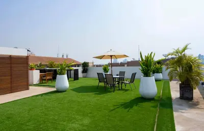 a patio with grass and white vases and a table and chairs at The Tivoli Hotel in Bangkok