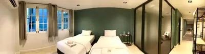 a bedroom with two beds and a green wall at Alley living rama8 in Bangkok