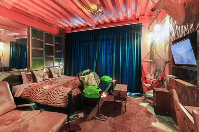 a bedroom with a bed and a couch and a television at MeStyle Garage Hotel in Bangkok